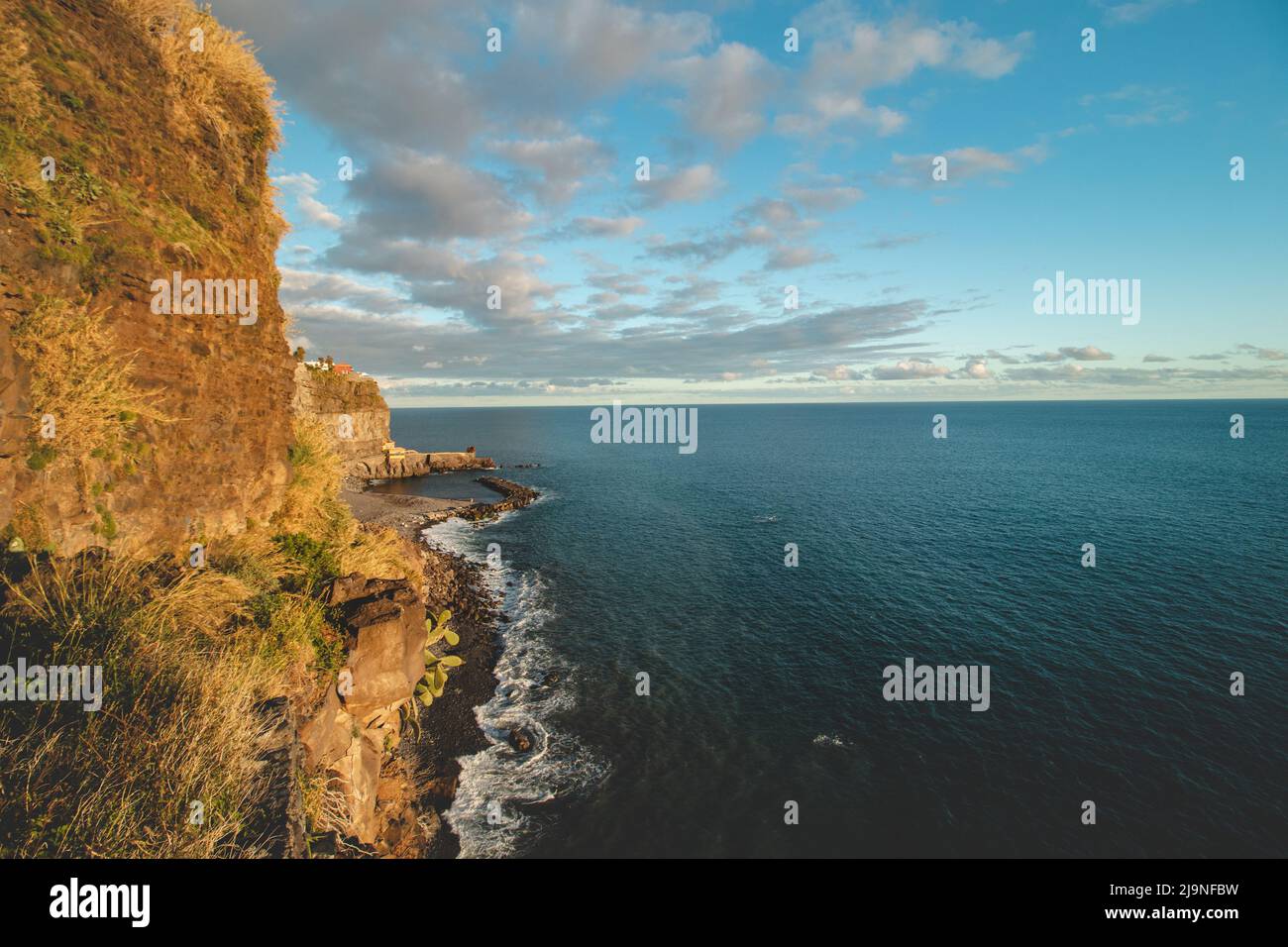 Coucher de soleil sur la côte atlantique au large de l'île de Madère, Portugal. Pierres massives illuminées de lumière dorée à Ponta do sol. Découverte de Madère. Banque D'Images