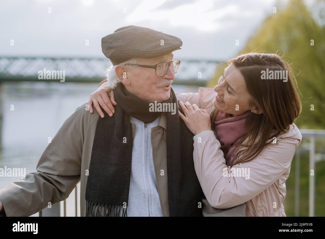Fille adulte embrassant son père aîné à l'extérieur dans le parc le jour du printemps. Banque D'Images