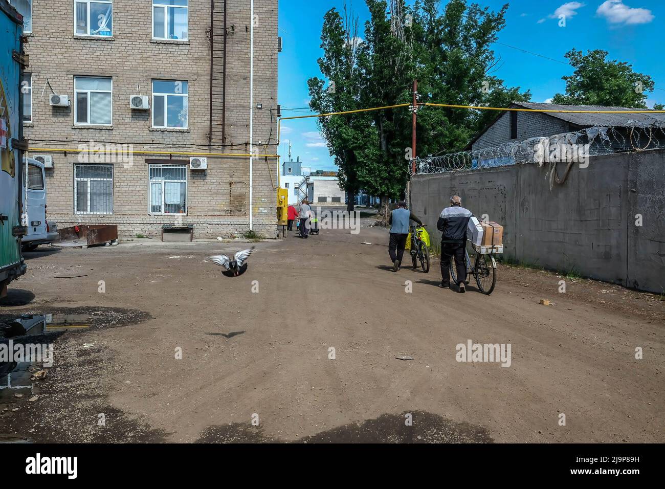 23 mai 2022, Severodonetsk, Ukraine: Des civils vus quittant le centre de distribution de l'aide humanitaire de la ville avec des boîtes d'aide humanitaire. Severodonetsk, la plus grande ville sous contrôle ukrainien de la province de Luhansk, a été soumise à une artillerie intense et à des tirs de missiles de l'armée russe. La ville est presque isolée par le reste de la région, il y a une route principale reliant la ville à Kramatorsk, l'armée russe essaie de l'occuper et du contrôler pour couper les provisions et les approvisionnements à la ville. Les experts militaires suggèrent la possibilité que Severodonetsk tombe en état de siège selon le Banque D'Images