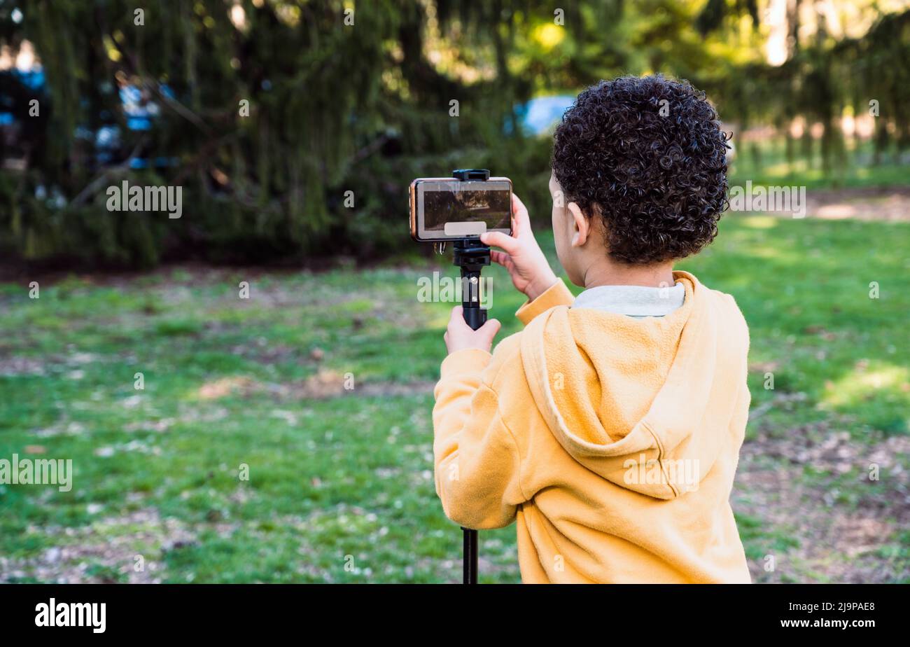 Jeune garçon photographe prenant des photos avec un téléphone portable à l'extérieur dans l'espace de copie nature. Banque D'Images