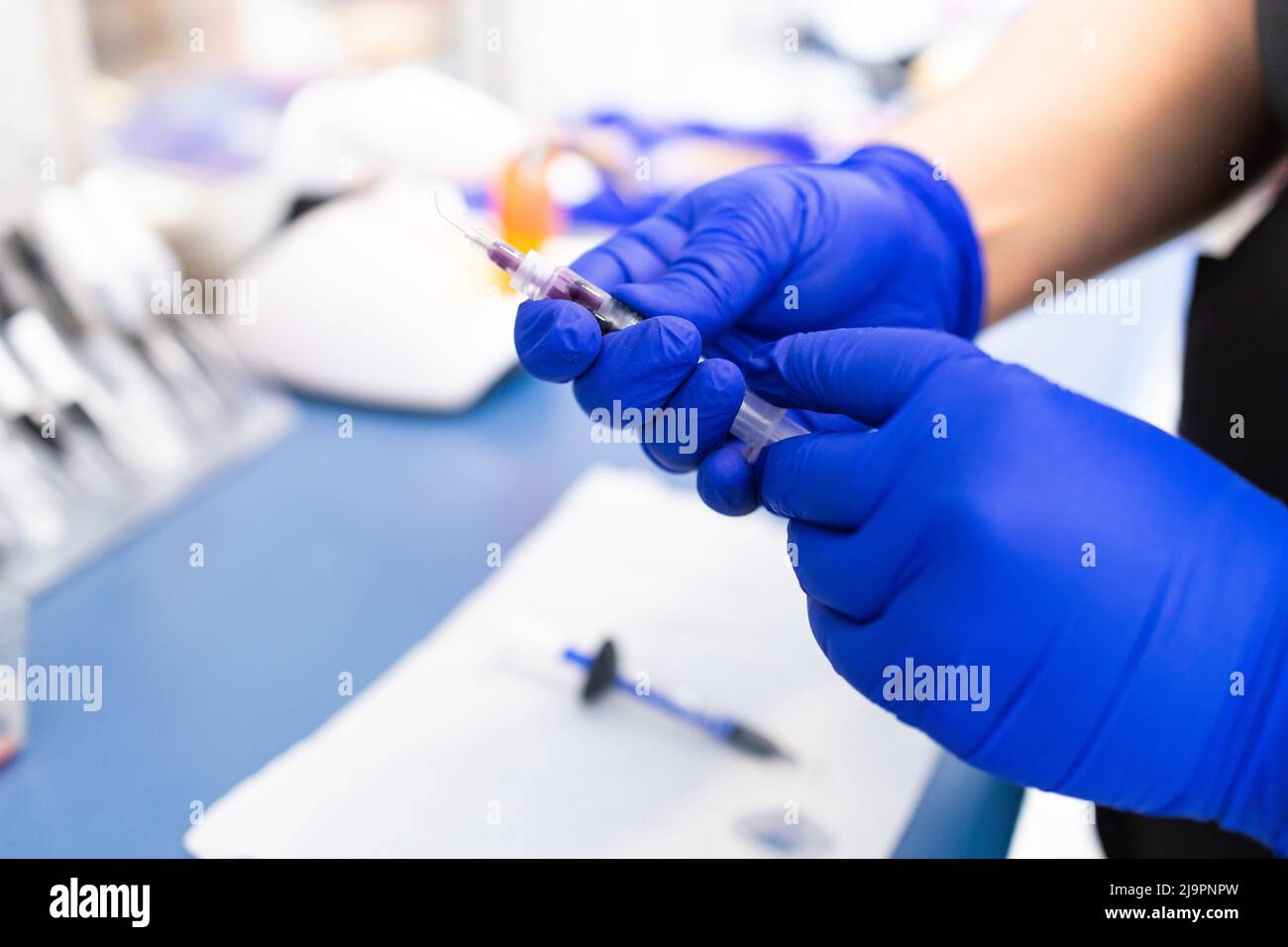 Les mains du dentiste préparent la seringue pour donner l'anesthésie dentaire à son patient. Mise au point sélective. Banque D'Images