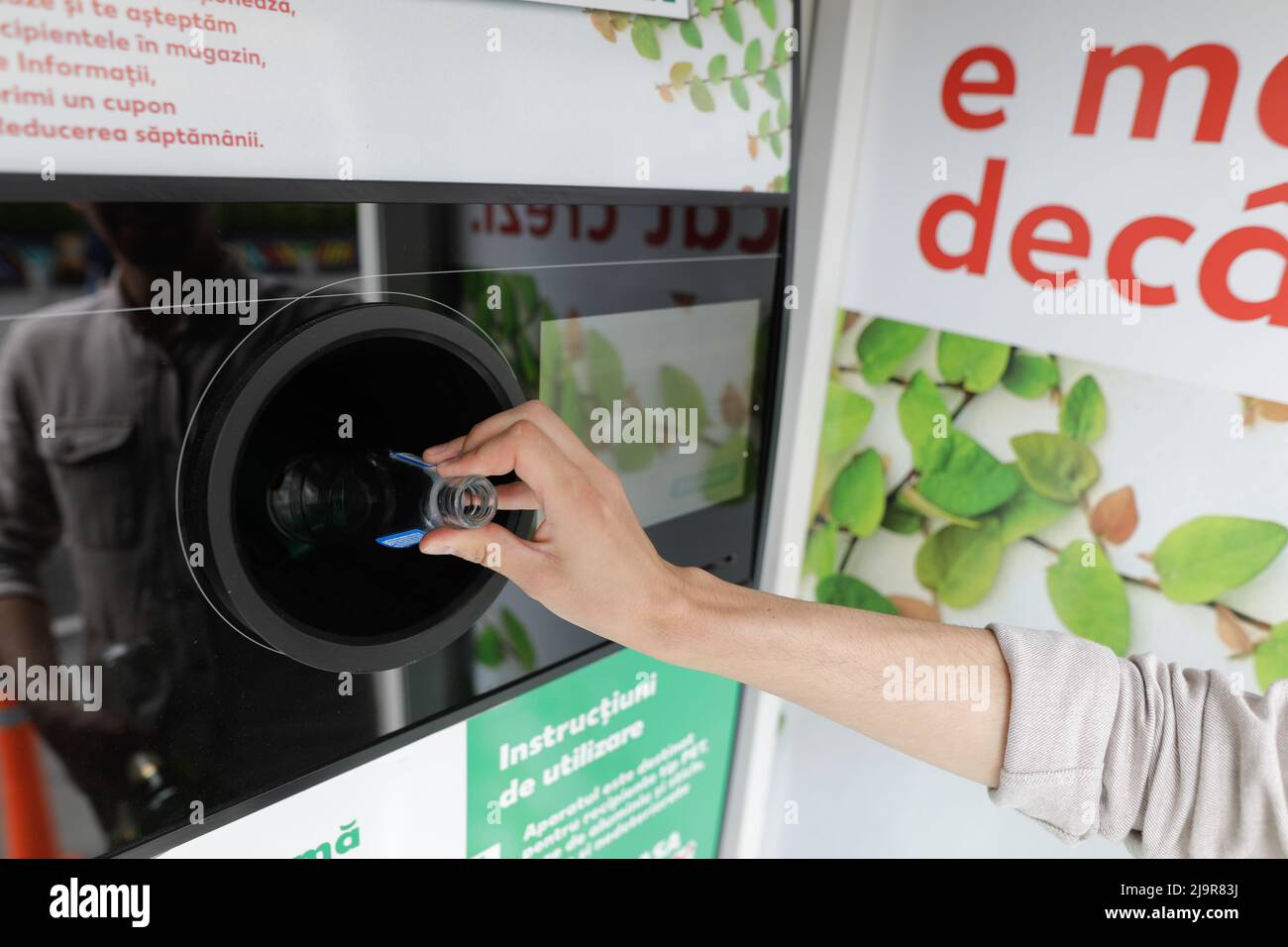 Bucarest, Roumanie - 25 mai 2022: Détails avec les mains d'un homme introduisant des bouteilles en verre dans un équipement de recyclage. Banque D'Images