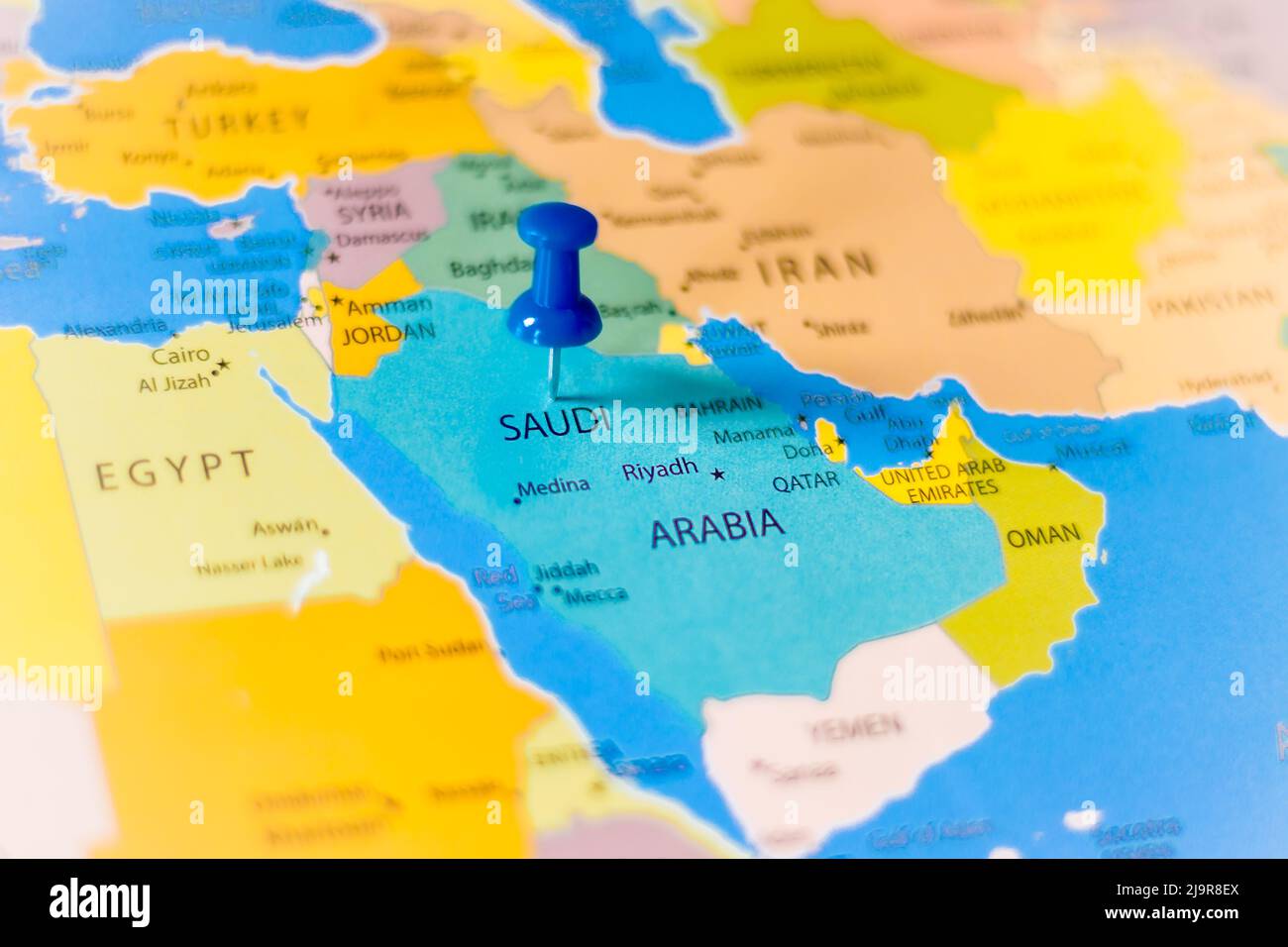 Punaise bleue pointant vers l'Arabie saoudite sur une carte politique du monde Banque D'Images