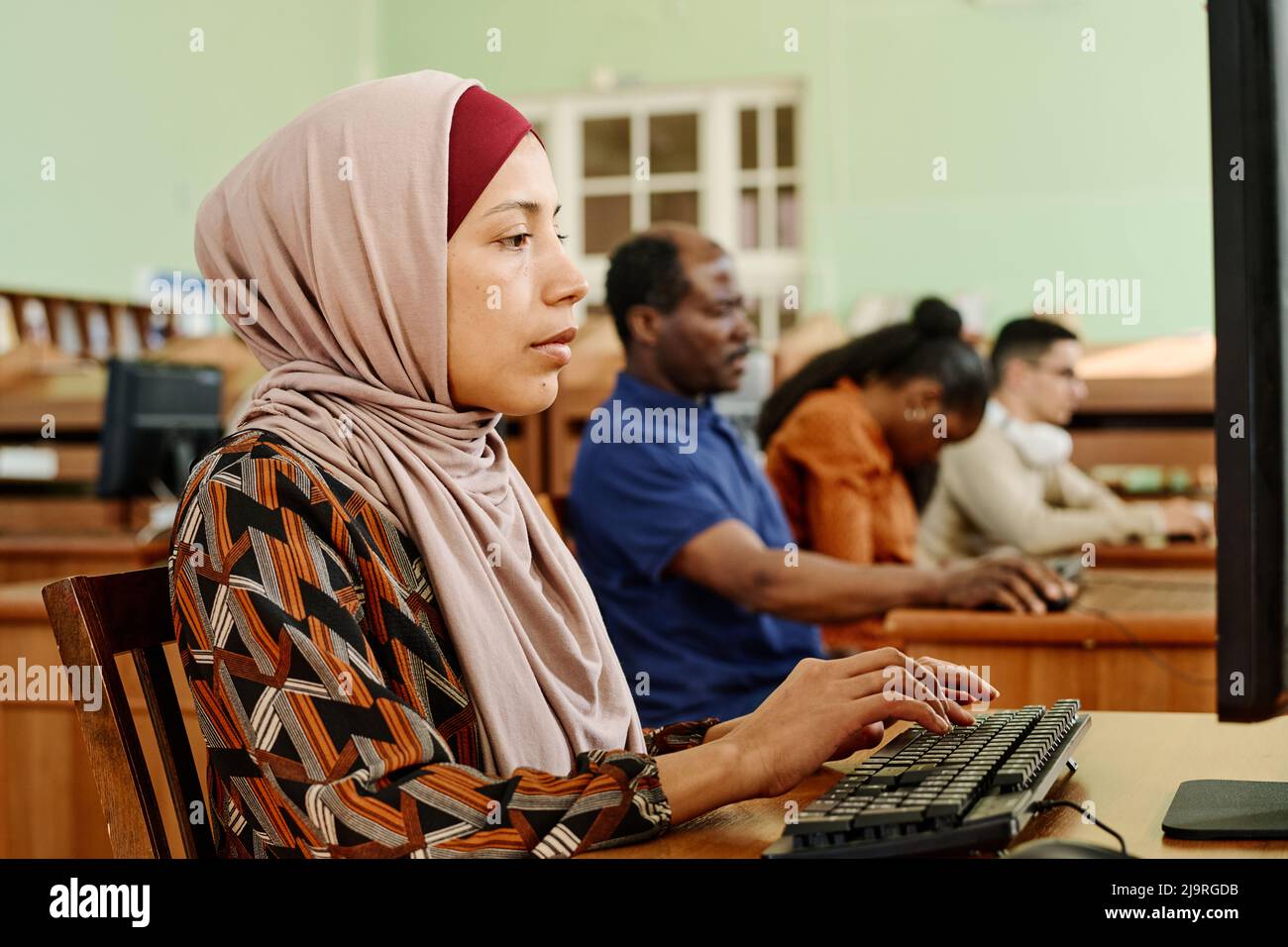 Jeune femme adulte du Moyen-Orient portant le hijab travaillant sur un ordinateur dans une bibliothèque universitaire Banque D'Images