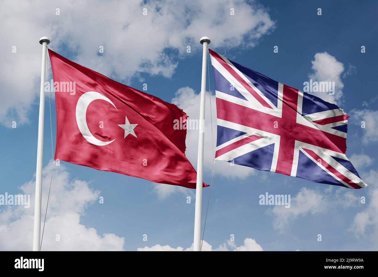 Turquie et Royaume-Uni deux drapeaux sur les mâts et fond bleu ciel nuageux Banque D'Images