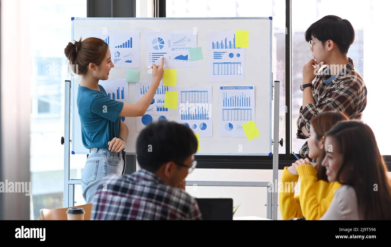 Une jeune femme et son collègue donnent la présentation d'une nouvelle stratégie de marketing sur le tableau de conférence. Banque D'Images