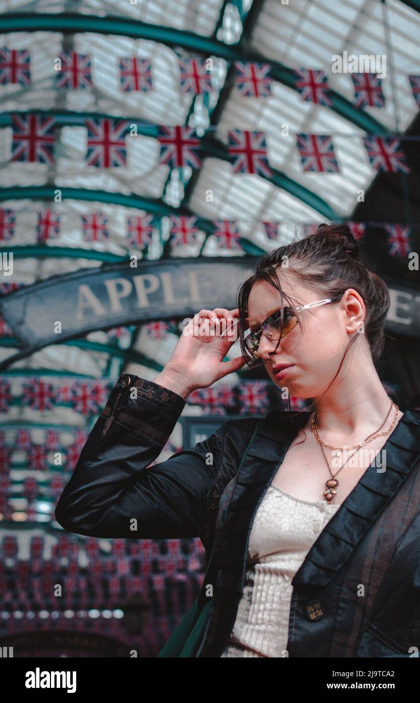 Une jeune femme se tenant devant le Apple Market à Covent Garden Londres avec Union Jack qui vole derrière elle. Banque D'Images