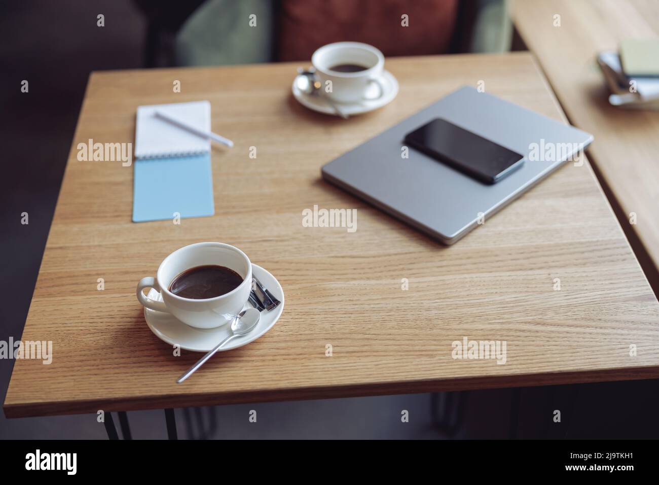 Table en bois avec tasses blanches de café et objets d'affaires. Ordinateur portable et téléphone. Prêt pour la réunion. Banque D'Images