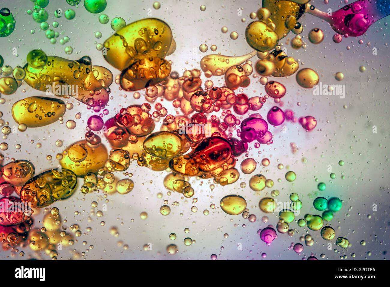 De grandes gouttes d'eau de plusieurs couleurs flottent dans un liquide transparent Banque D'Images