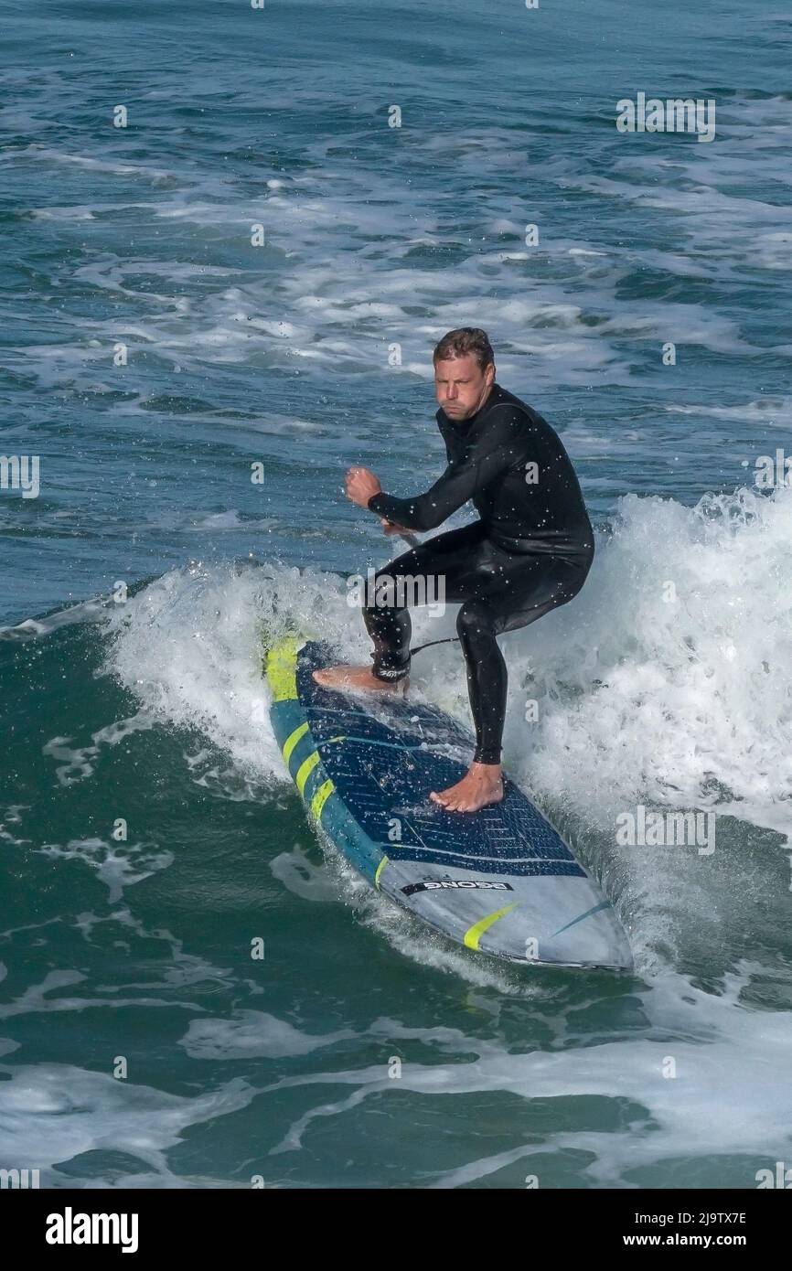 Un Paddleboarder debout déterminé qui fait une vague à Fistral, à Newquay, dans les Cornouailles. Banque D'Images