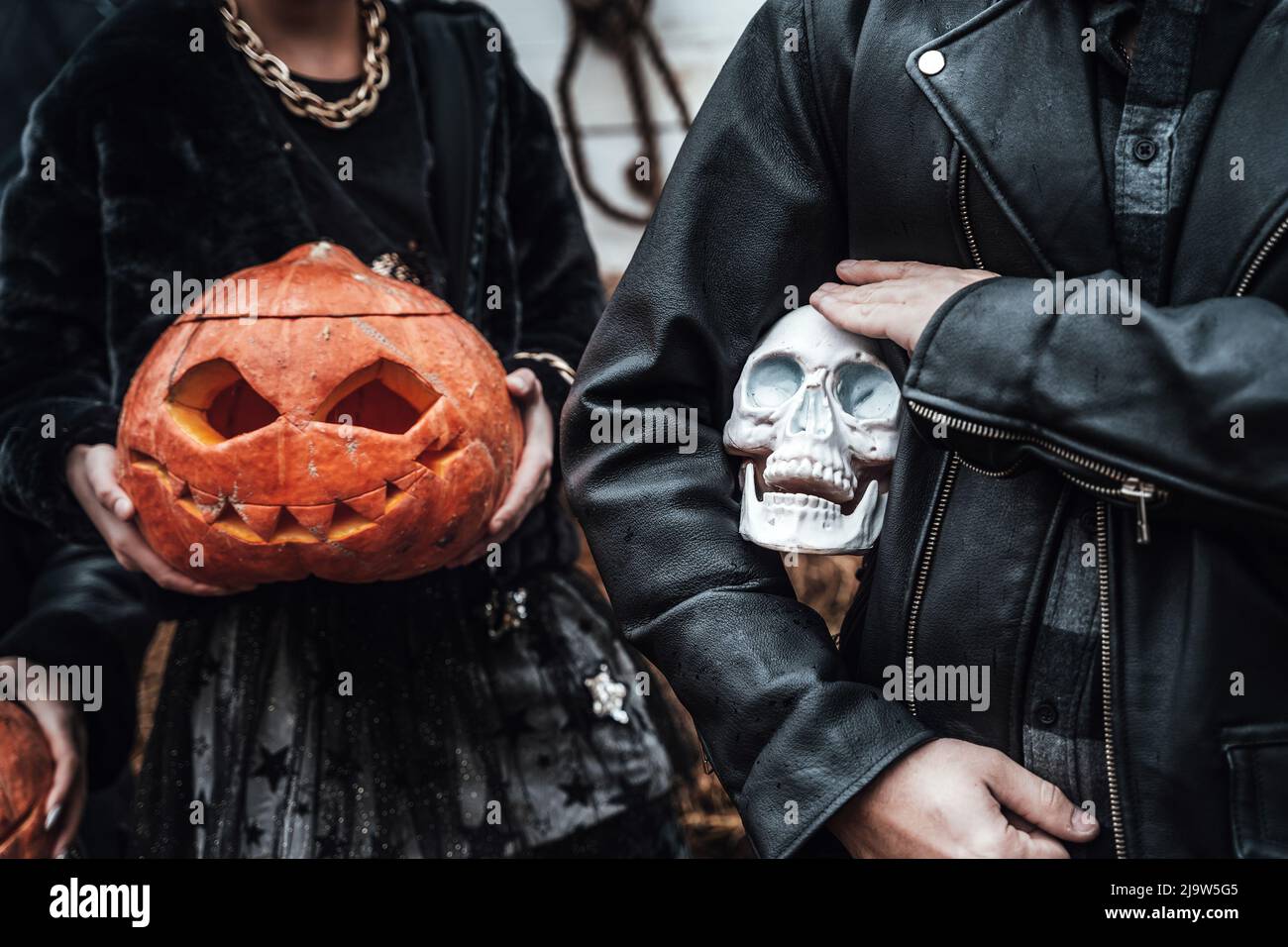 Citrouilles, citrouille, citrouille, citrouille et crâne dans les mains. Père de famille effrayant, fille célébrant halloween. Costumes de sorcière élégants, images. Horreur, plaisir chez les enfants Banque D'Images