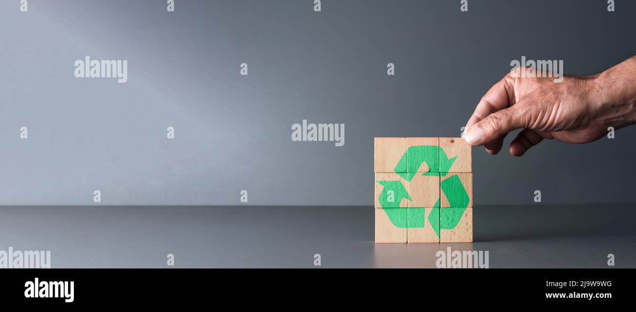 main posant des blocs de bois avec le symbole de recyclage avec fond gris et espace de copie, journée mondiale de la terre et journée mondiale de l'environnement . Banque D'Images