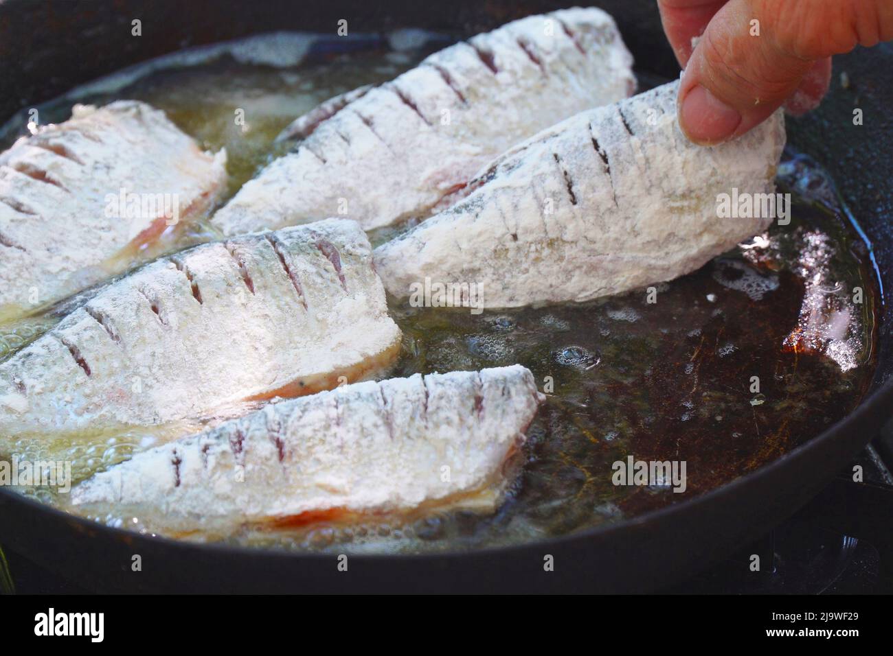 Un petit poisson de rivière roulé dans la farine est frit dans l'huile dans  une poêle Photo Stock - Alamy