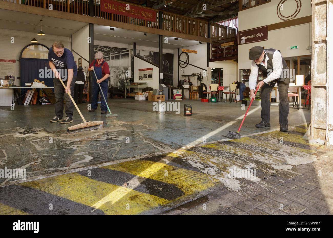 Des bénévoles balayant et nettoyant le hangar de moteurs, au musée Charles Burrell Steam, l'ancien atelier de peinture de Charles Burrell & Sons, Thetford Banque D'Images