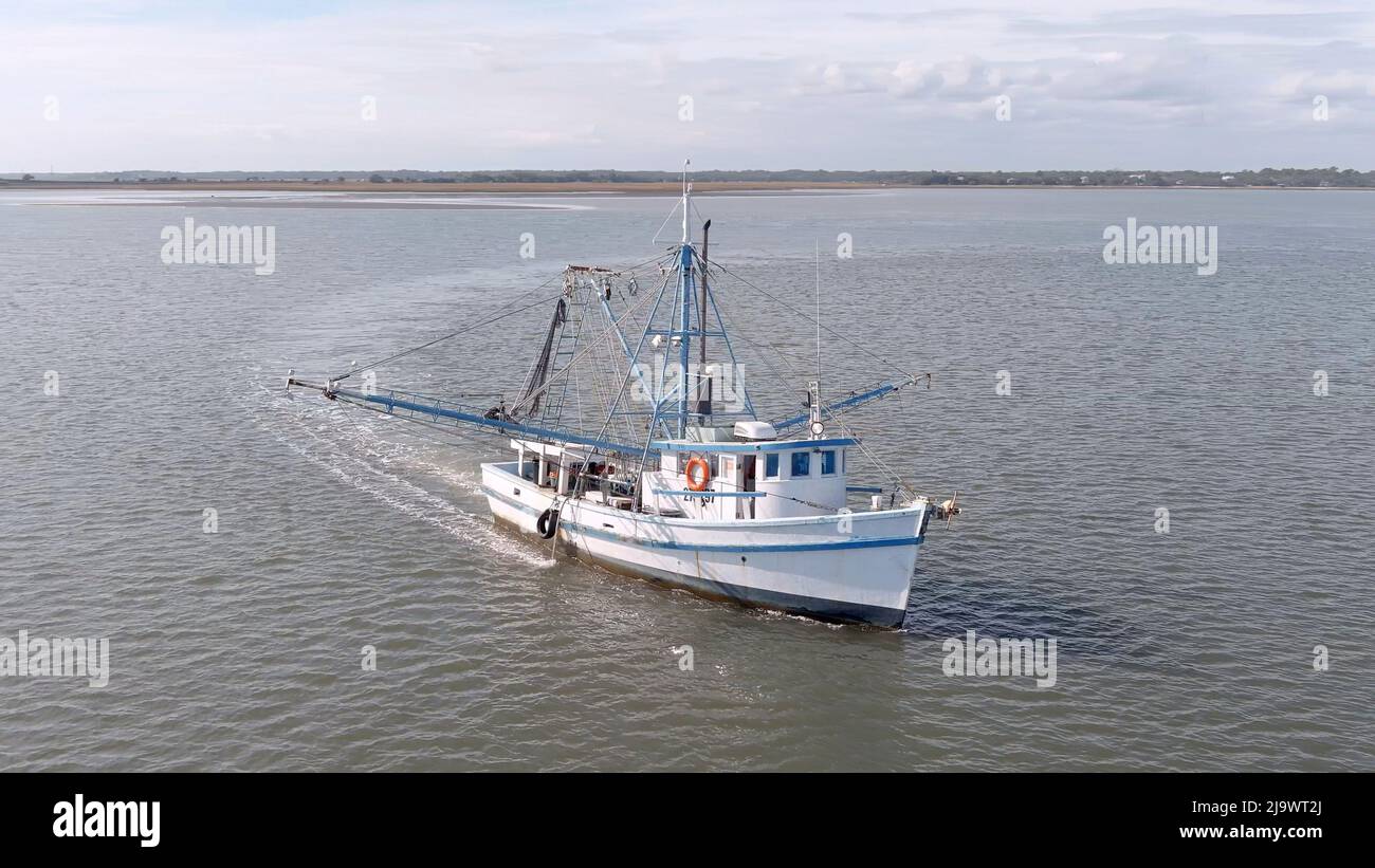 Vue aérienne basse d'un bateau à crevettes tirant des filets au large de la côte de Caroline du Sud, États-Unis. Banque D'Images