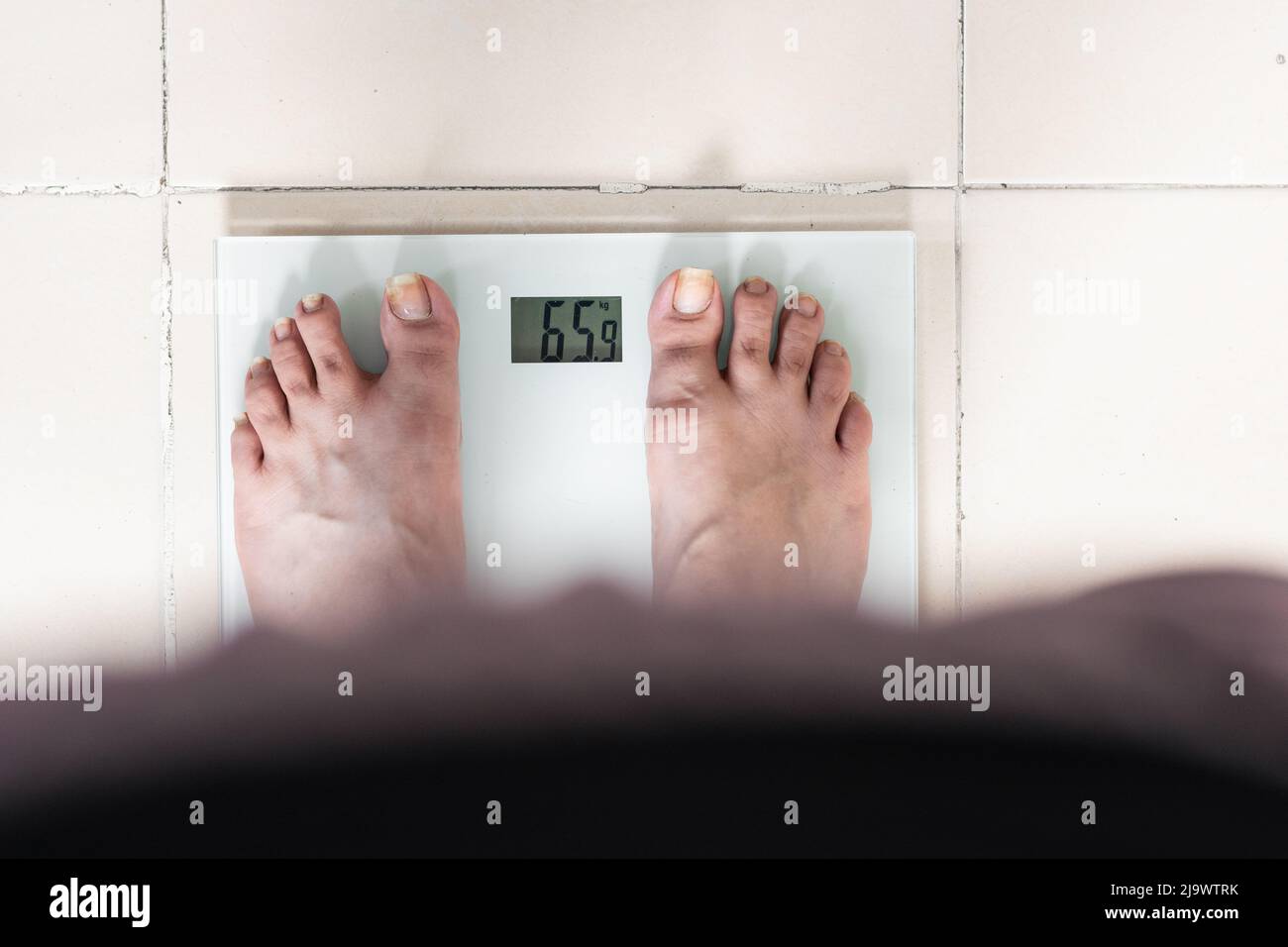 vue détaillée des pieds d'une fille prenant son poids sur une balance, en regardant le calcul exact du point de vue de la femme. soins personnels et régime pour Banque D'Images