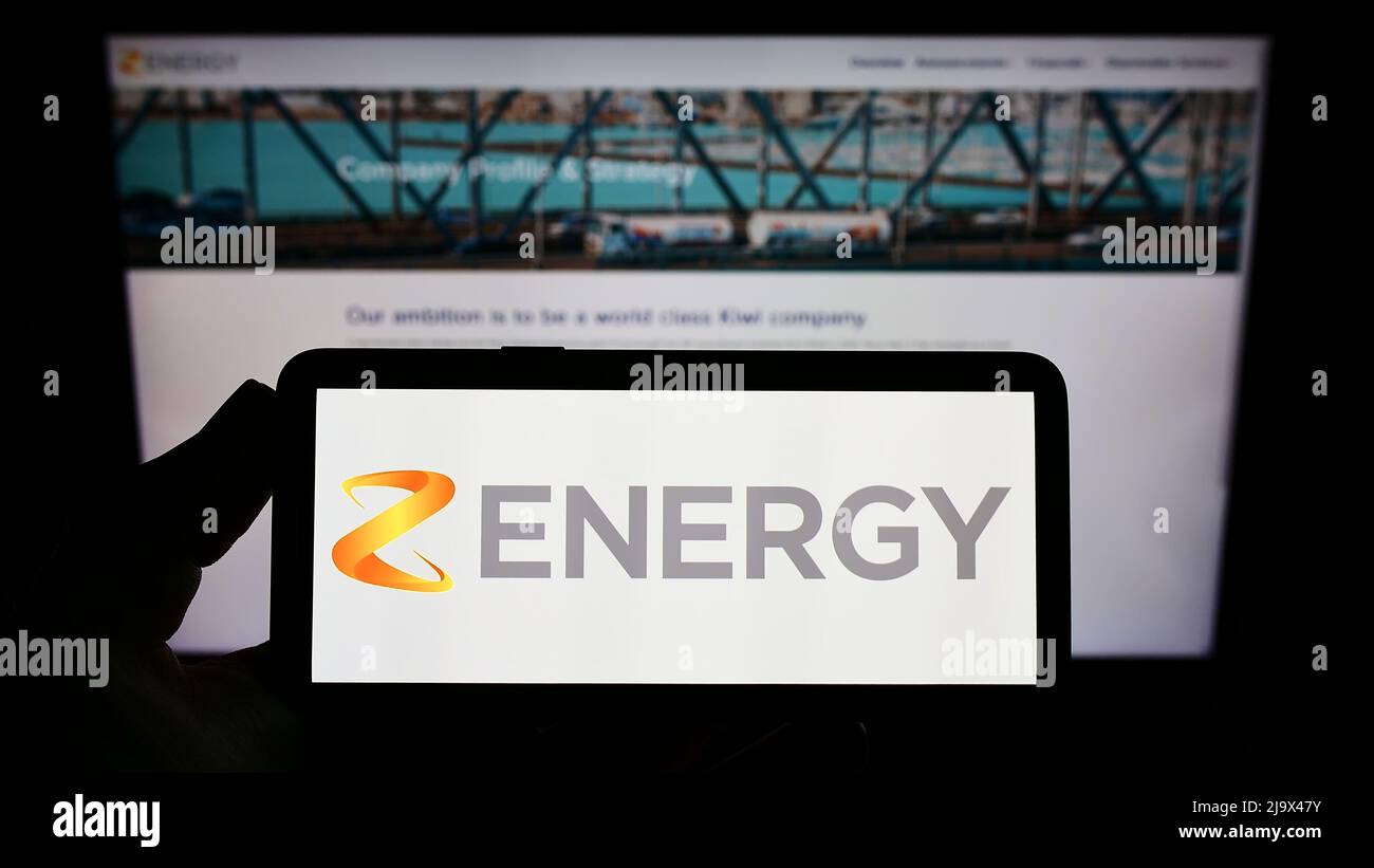 Personne tenant un smartphone avec le logo de la société néo-zélandaise Z Energy Limited à l'écran devant le site Web. Mise au point sur l'affichage du téléphone. Banque D'Images