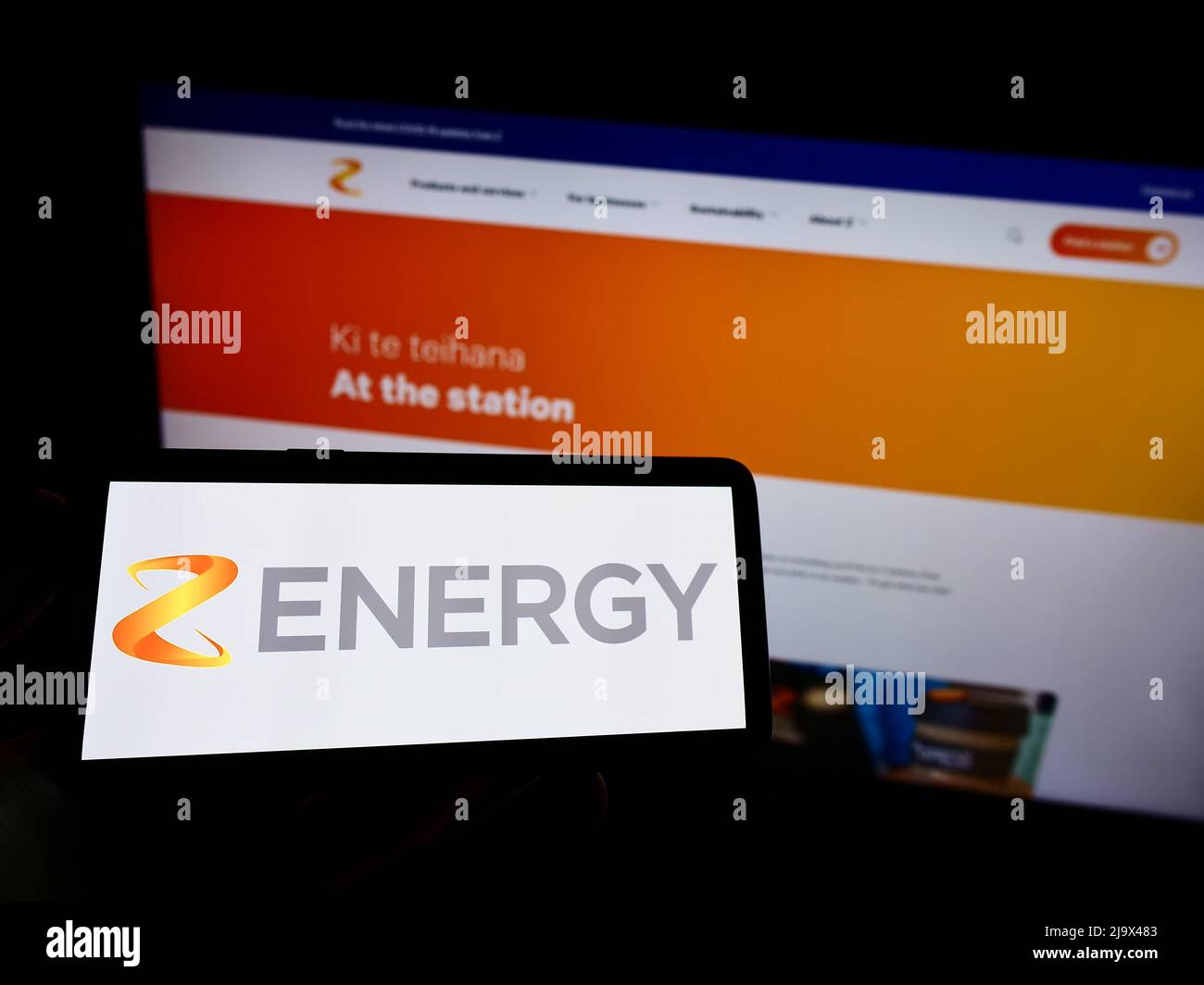 Personne tenant un téléphone portable avec le logo de la société néo-zélandaise Z Energy Limited à l'écran en face de la page Web d'affaires. Mise au point sur l'affichage du téléphone. Banque D'Images