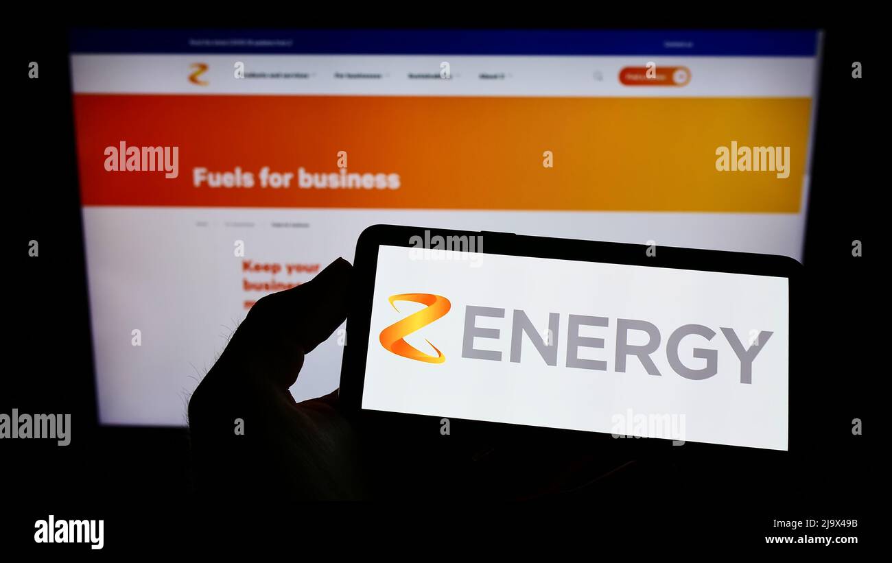 Personne tenant un téléphone portable avec le logo de la société néo-zélandaise Z Energy Limited à l'écran en face de la page Web d'affaires. Mise au point sur l'affichage du téléphone. Banque D'Images