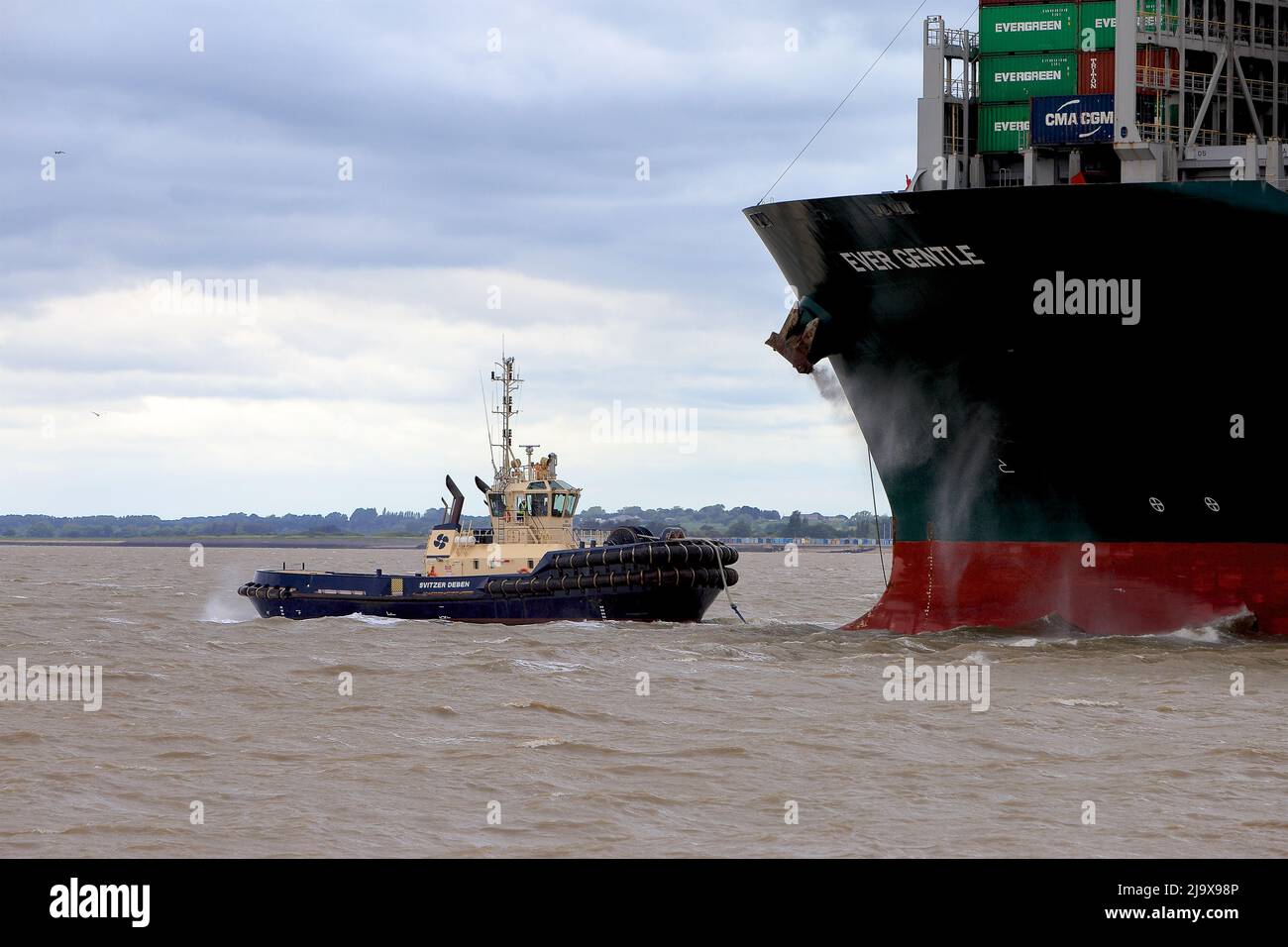 Remorqueur Svitzer Deben aidant le navire à conteneurs toujours doux pour quitter le port de Felixstowe dans des conditions météorologiques défavorables. Banque D'Images