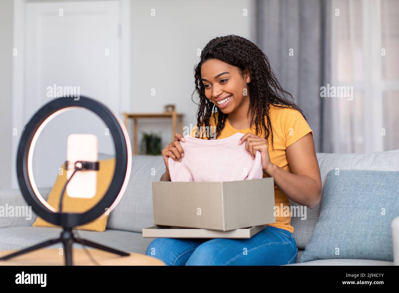 Populaire afro-américain de la mode blogueur enregistrement vidéo de l'examen de nouveaux vêtements, montrant chemise à la caméra de téléphone portable Banque D'Images