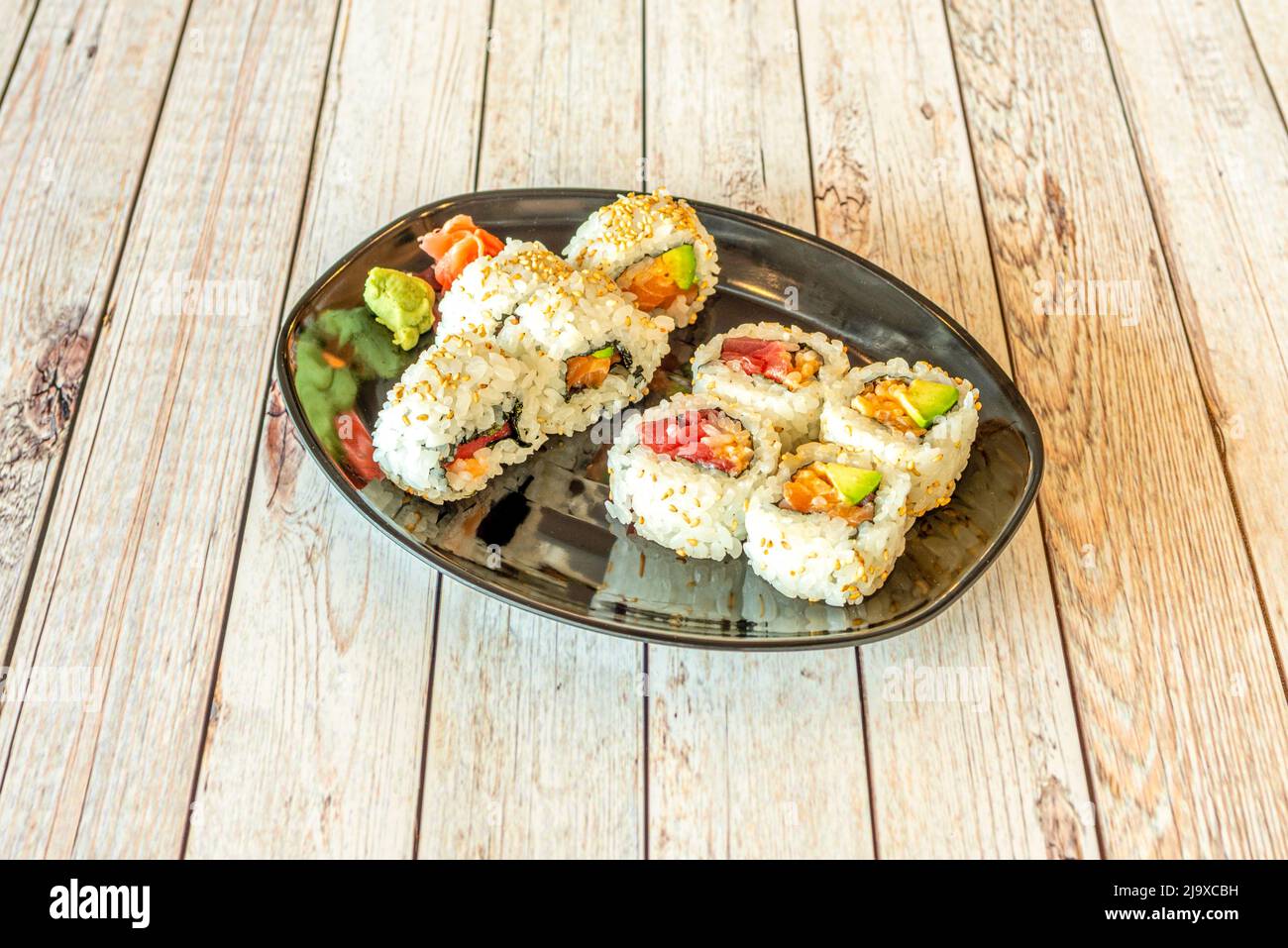 Sushi californien à base d'uramaki avec thon rouge, avocat, saumon norvégien, wasabi, algues nori et riz japonais Banque D'Images