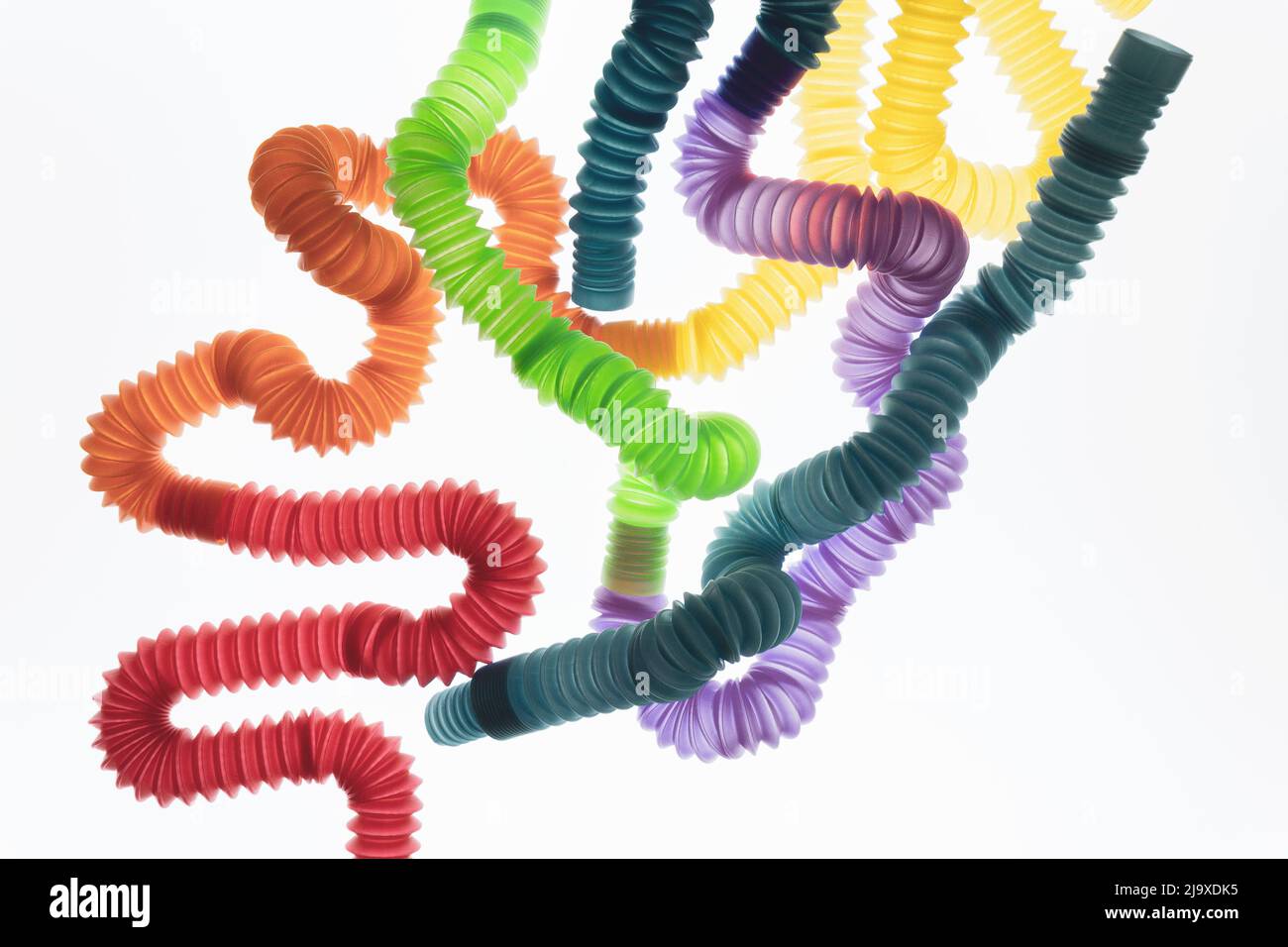 Jouets tendance pour enfants — tubes pop colorés sur fond blanc. Jeu de formes et couleurs différentes tuyau ondulé. Banque D'Images