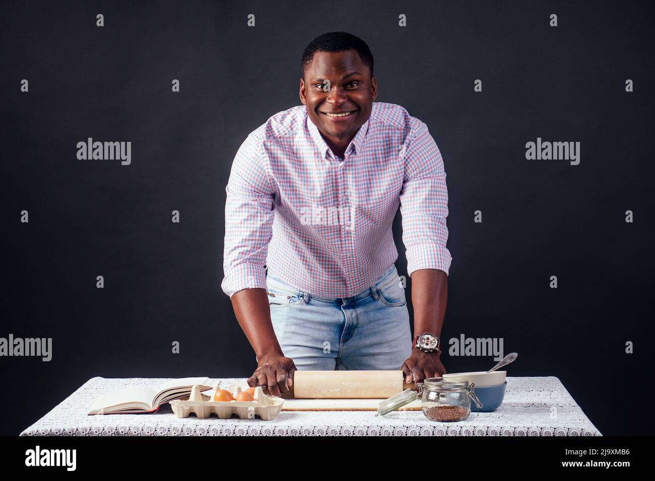 Beau et jeune africain africain préparant des gâteaux faits maison Pie américaine de pâte fraîche mains sales par la farine, sur la table sont des oeufs, rouleau Banque D'Images