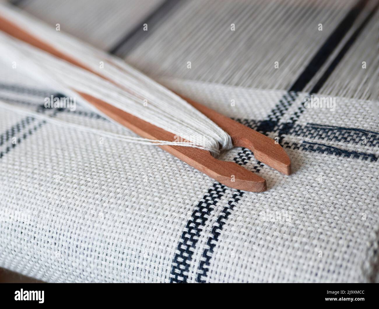 Projet de tissage noir et blanc. Navette en bois avec fil sur la main, gros plan Banque D'Images