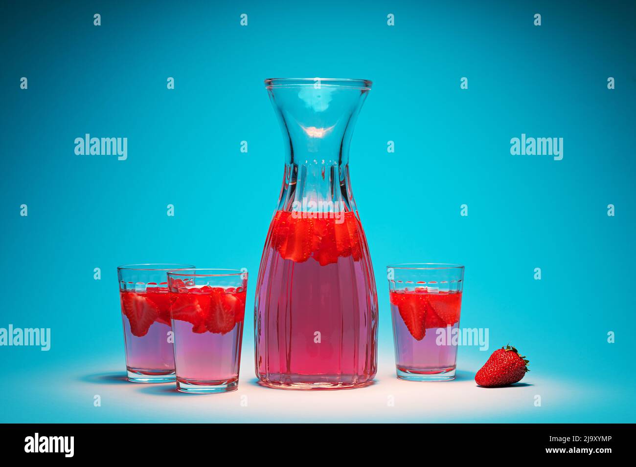Carafe et verres avec limonade aux fraises sur fond turquoise Banque D'Images