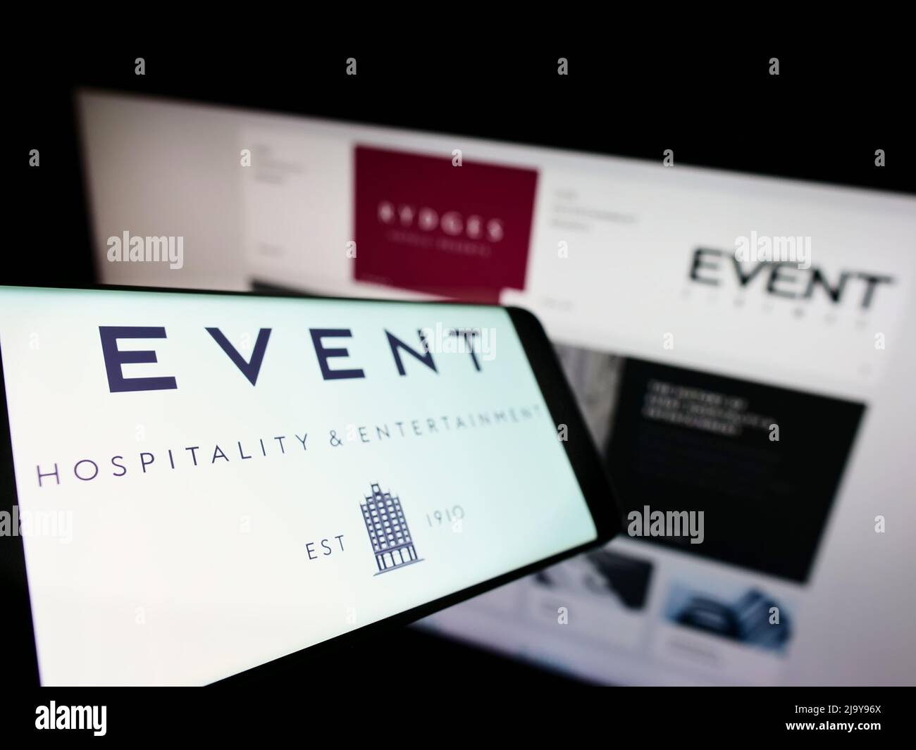 Smartphone avec logo de la société Event Hospitality Entertainment Ltd. Sur écran devant le site Web d'affaires. Mise au point à gauche de l'écran du téléphone. Banque D'Images