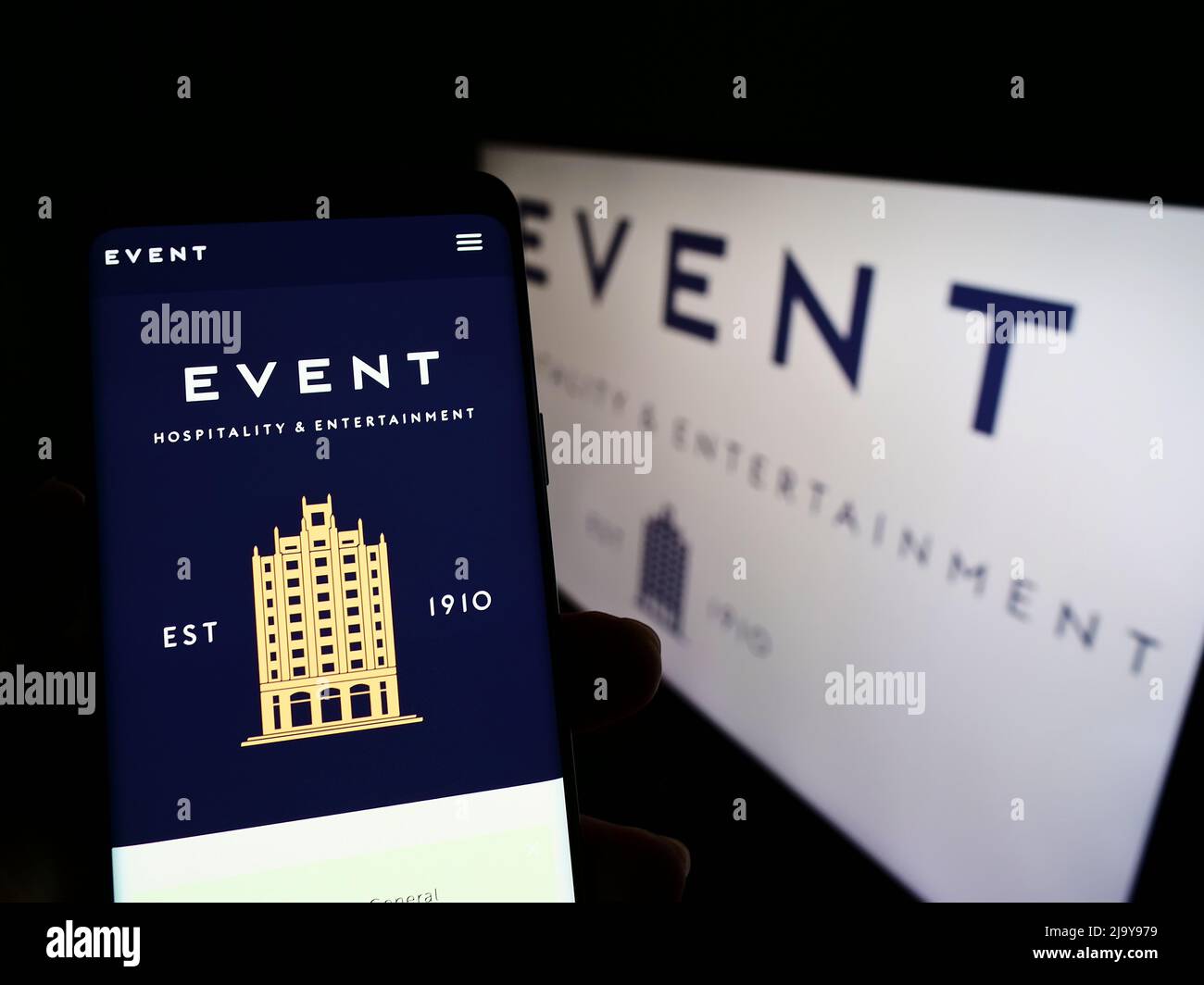 Personne tenant un téléphone cellulaire avec le site Web de la société Event Hospitality Entertainment Ltd. À l'écran avec logo. Concentrez-vous sur le centre de l'écran du téléphone. Banque D'Images