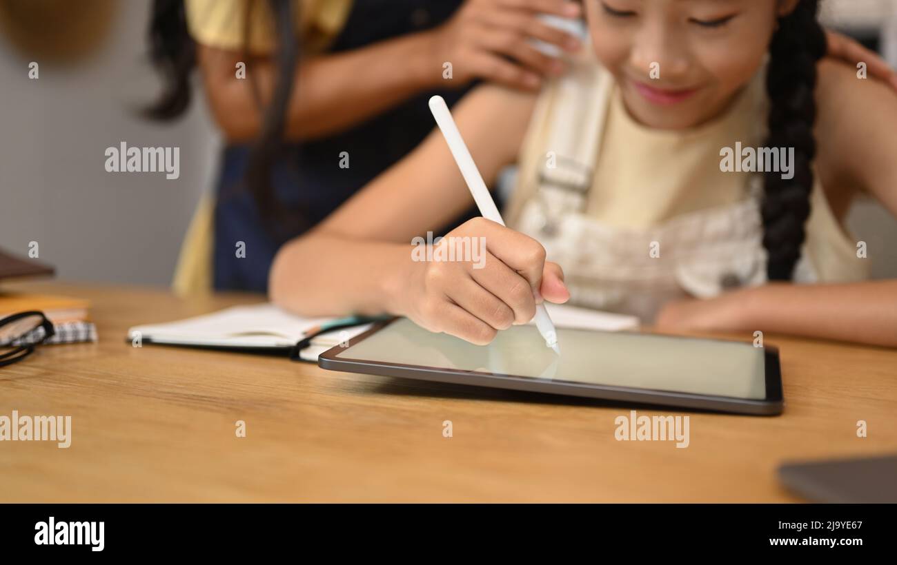 Jeune fille asiatique concentrée utilisant une tablette numérique, faisant des devoirs, étudiant en ligne sur le Web classe virtuelle Banque D'Images