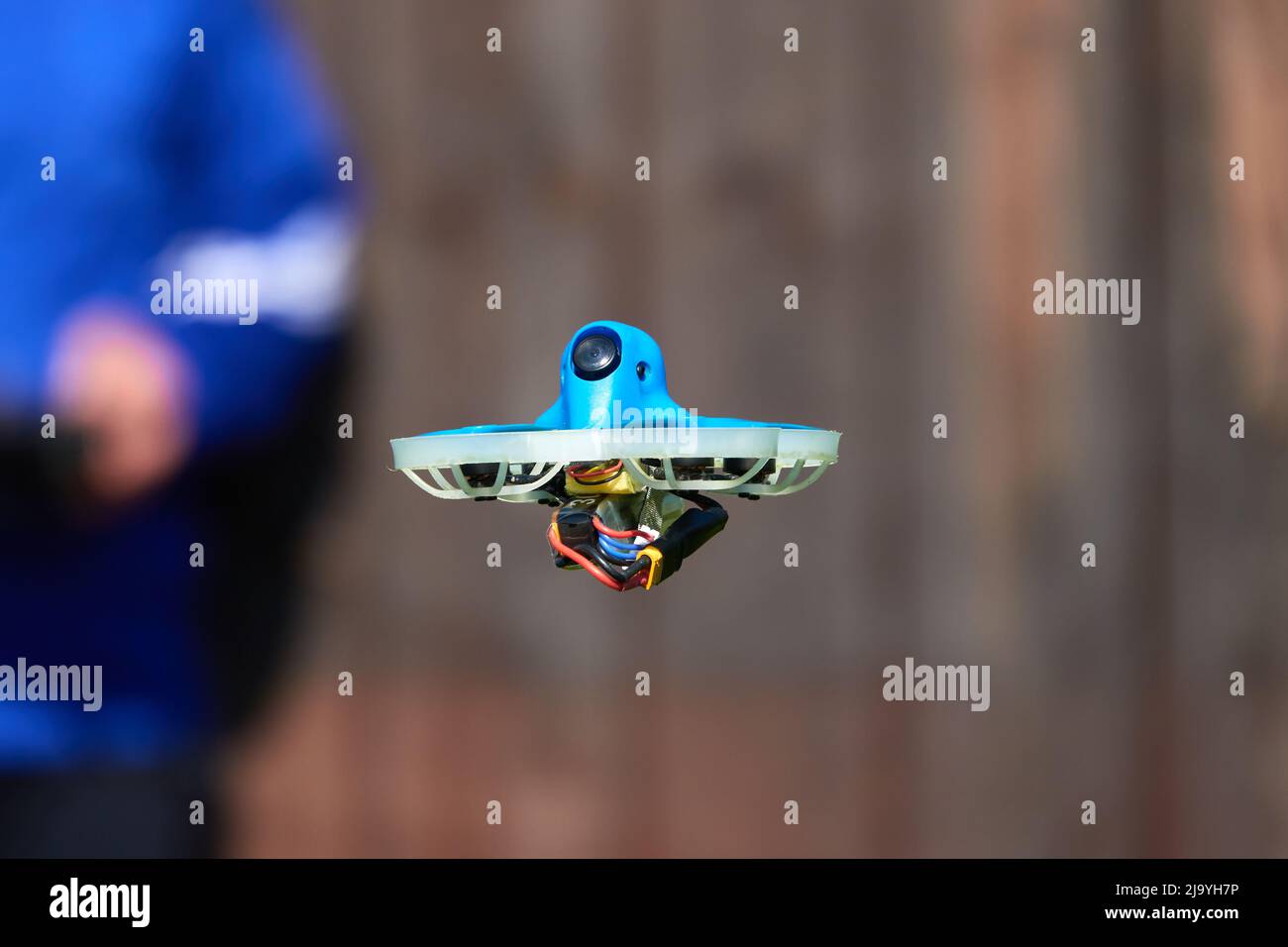 Le petit drone également la course quad en bleu est précisément contrôlée par le pilote humain, mur en marron comme fond.Allemagne. Banque D'Images