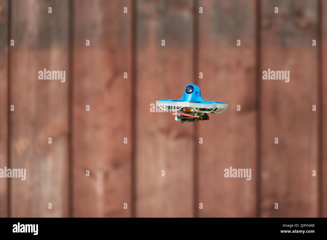 Petit drone également la course quad en bleu, voler sur brun panneau de fond en bois Allemagne. Banque D'Images