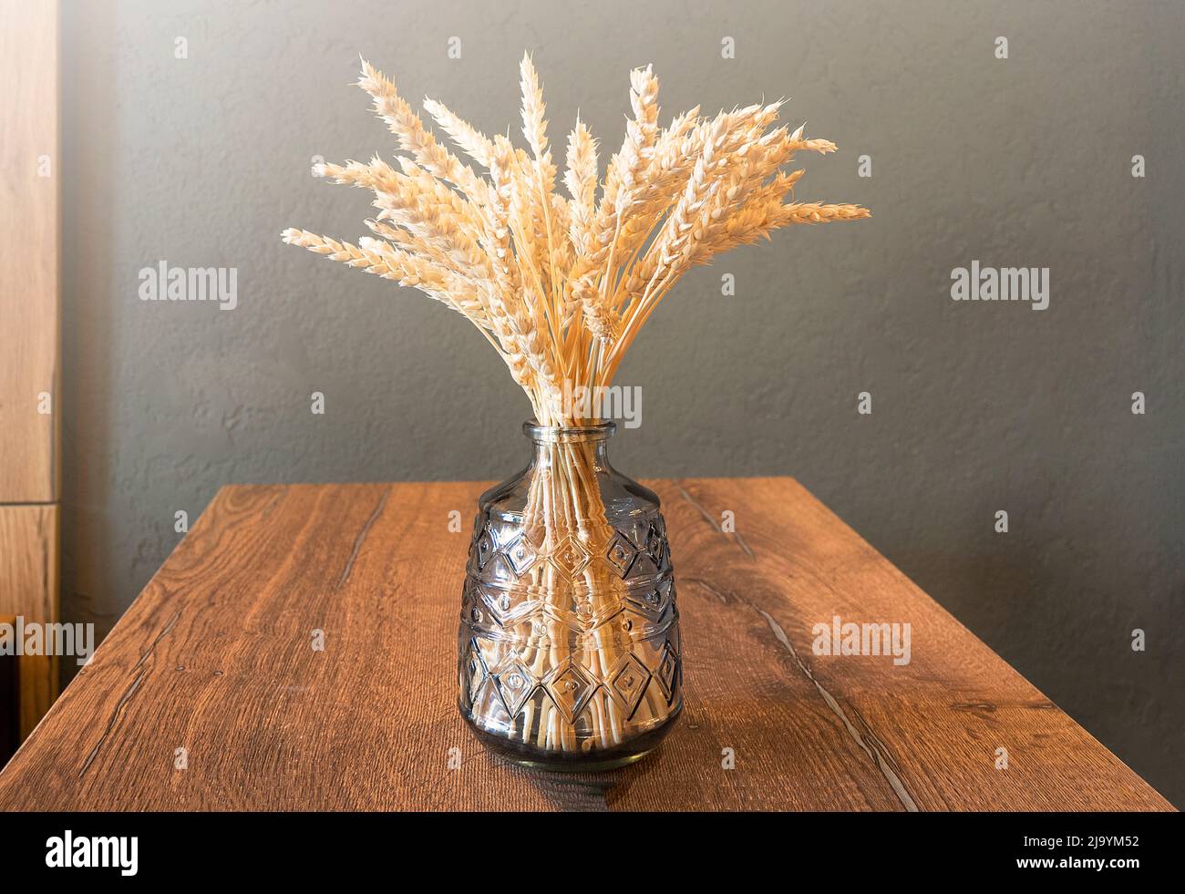 Composition simple avec vase en verre et bouquet sec avec oreilles de blé sur table en bois, encore la vie avec la lumière ensoleillée Banque D'Images