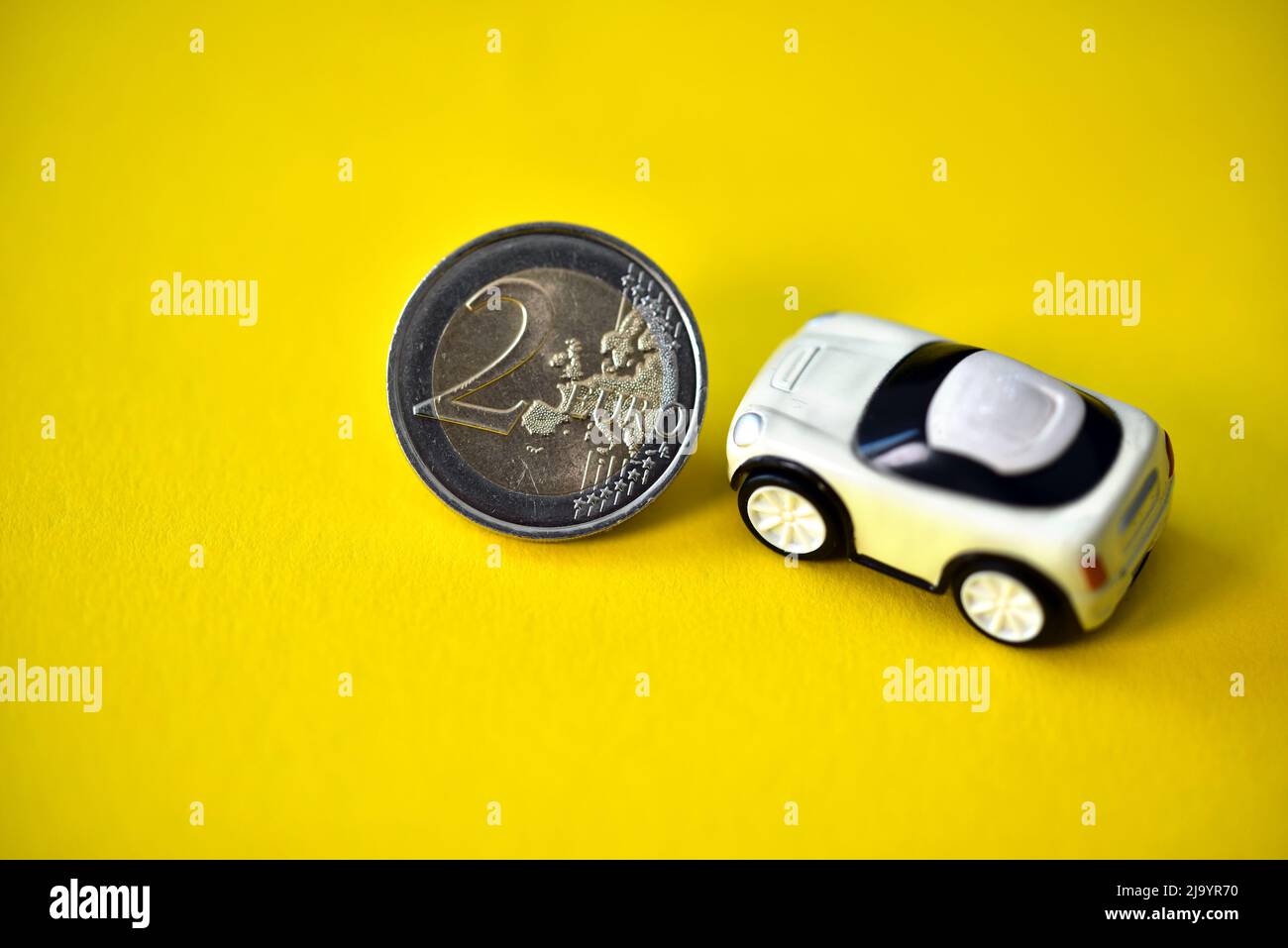 deux pièces de monnaie d'un euro avec une petite voiture-jouet Banque D'Images
