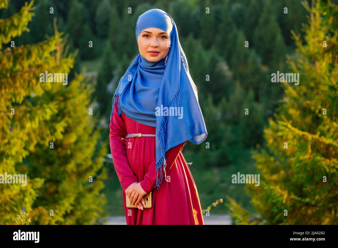 Portrait d'une belle femme musulmane aux yeux verts portant un foulard bleu visage fermé couvert d'aveil arrière-plan arbres forestiers dans le parc Banque D'Images