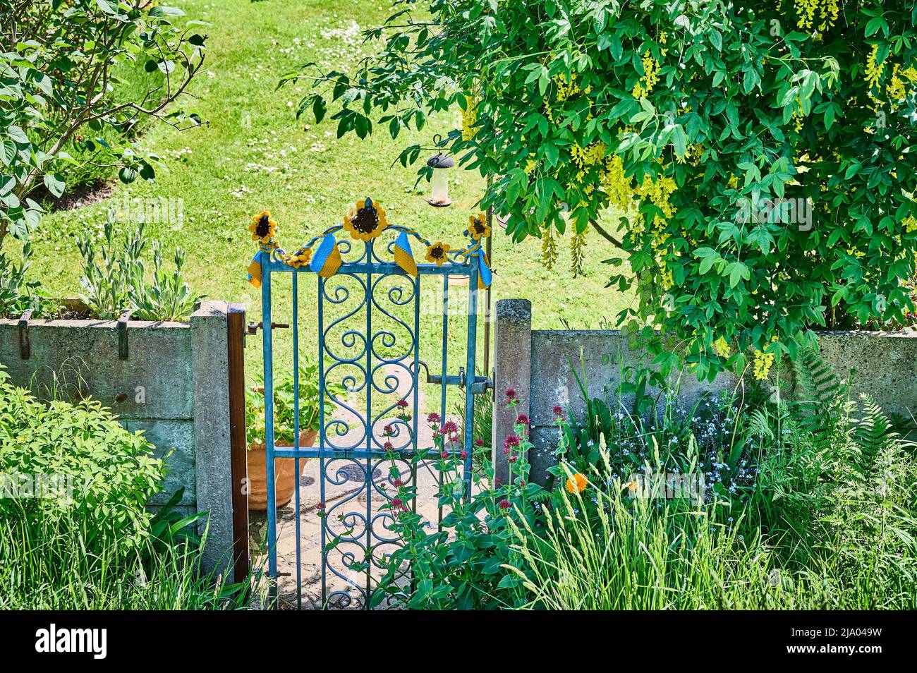 Entrée clôturée au jardin au printemps avec fleurs et drapeau ukrainien crocheté Banque D'Images