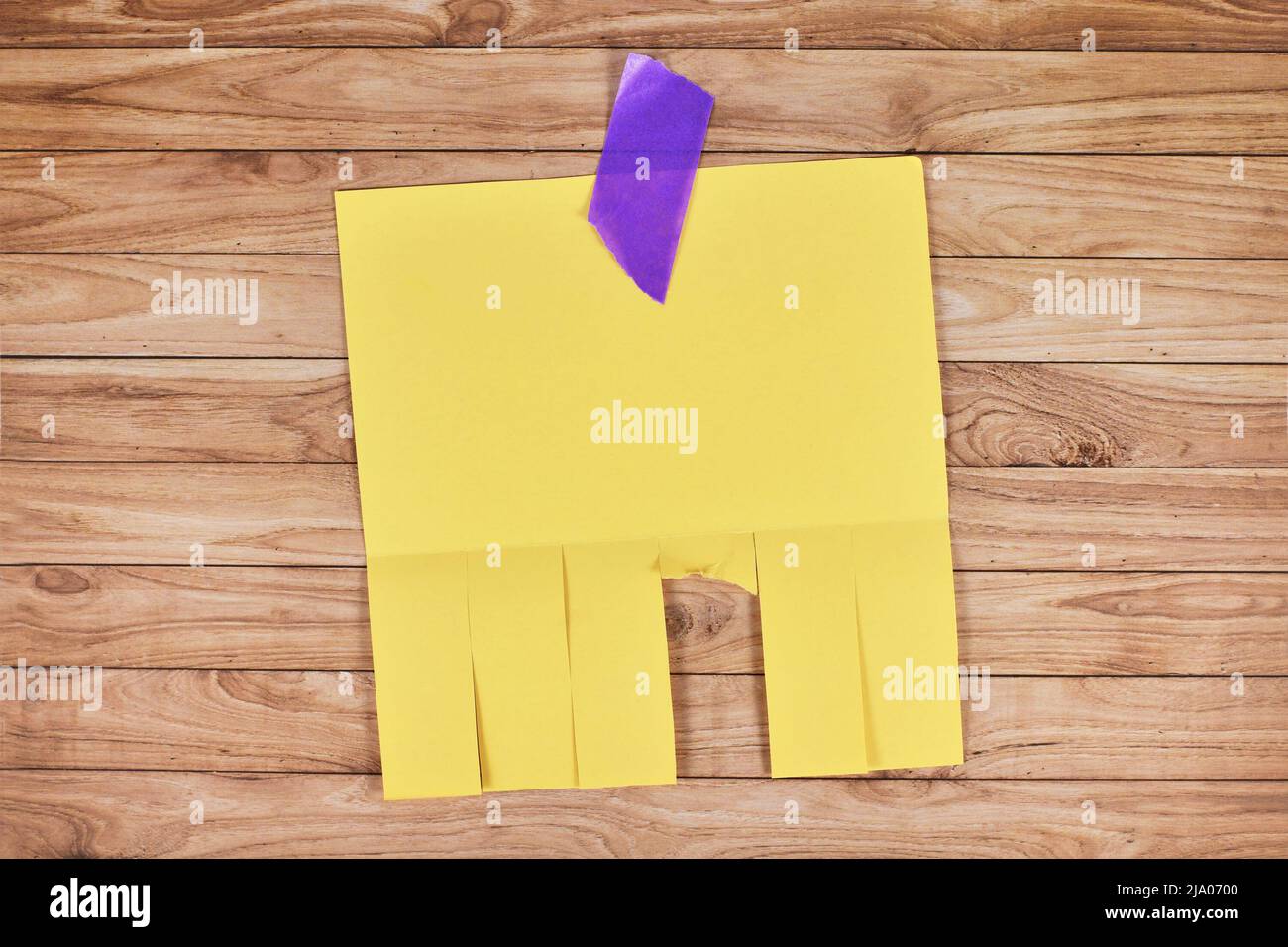 Note de papier de stub détachable jaune sans texte sur un mur en bois Banque D'Images