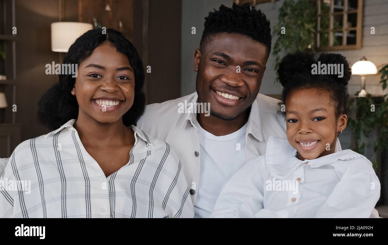 Joyeux portrait de famille africain. Parents avec fille gaie regardant l'appareil-photo riant cuddling à la maison souriant torrenie. Mère positive, père Banque D'Images