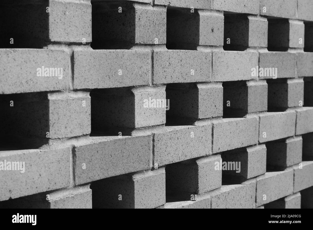 Mur de briques avec un motif répétitif et des ouvertures en noir et blanc. Banque D'Images
