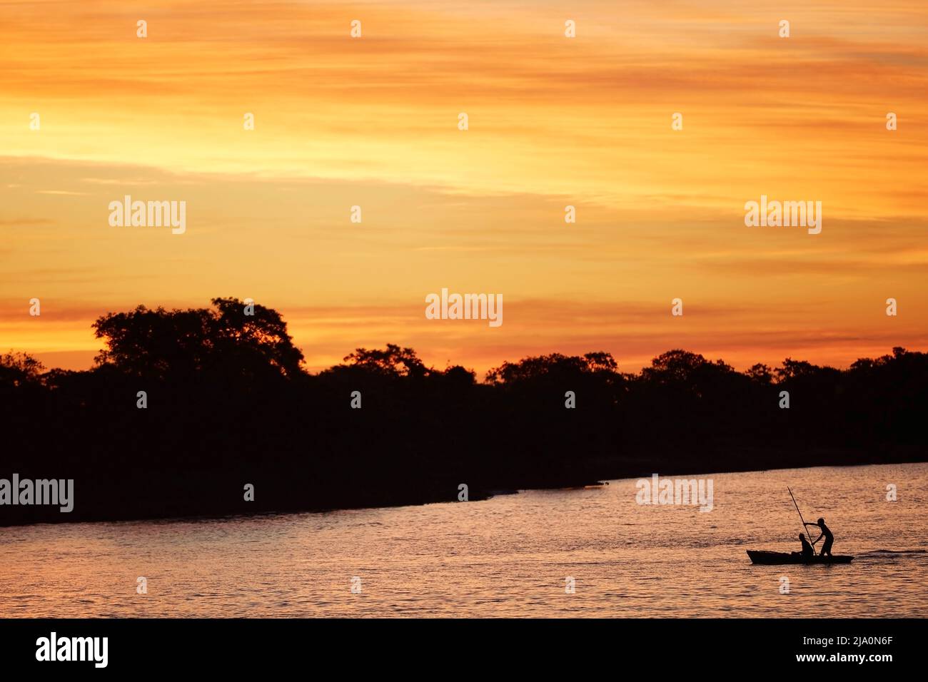 Silhouette de pêcheurs sur un petit bateau en bois sur la rivière Parana au crépuscule, Esquina, province de Corrientes, Argentine. Banque D'Images