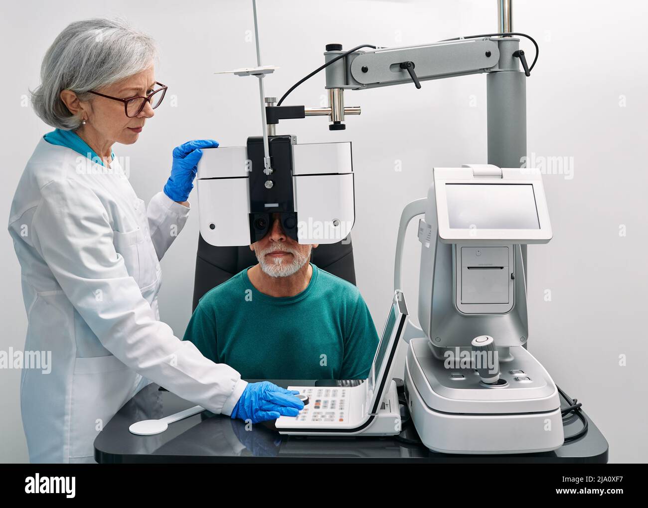 Optométriste effectuant un test de vision pour un patient mature utilisant un phoroptère moderne à la clinique d'ophtalmologie. Examen oculaire et diagnostic de la vision Banque D'Images