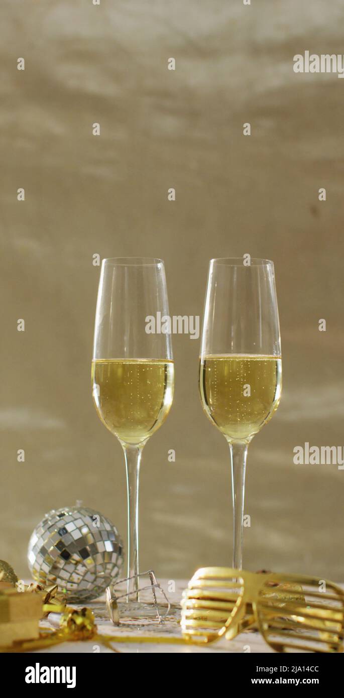 Image verticale de deux verres de champagne, mini disco ball et verres de fête Banque D'Images