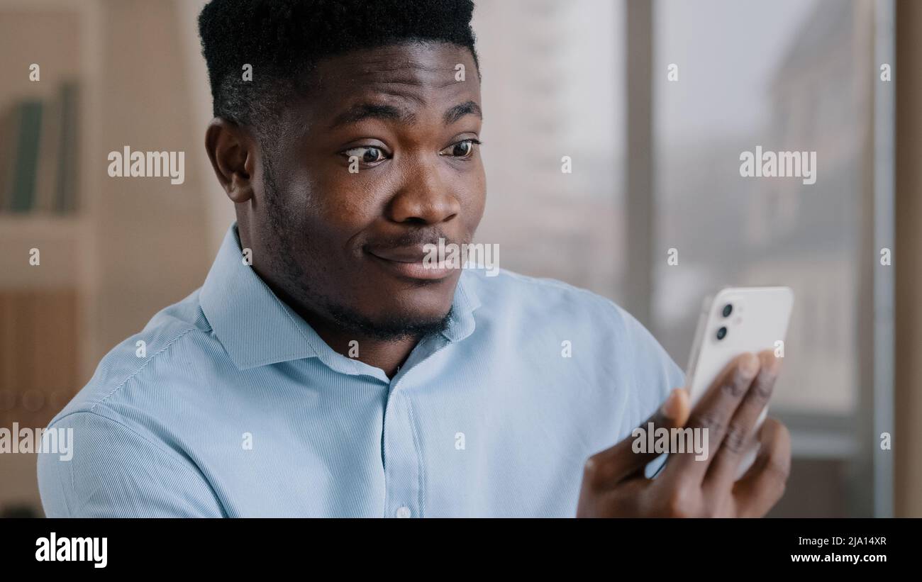 Un homme africain surpris un homme du millénaire 30s parle à distance sur téléphone mobile un homme américain adorable et adulte fait un appel vidéo choqué par soudain Banque D'Images