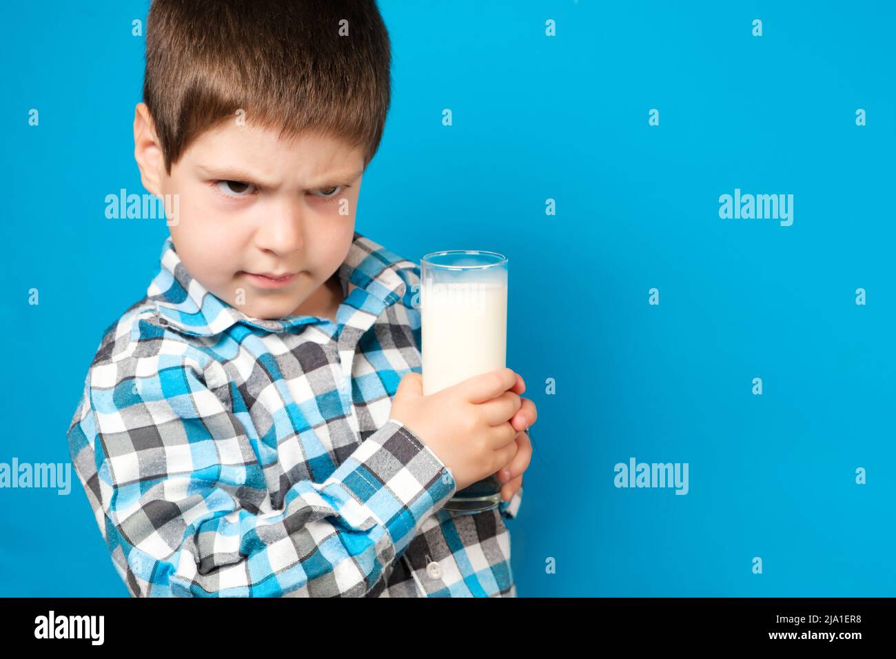 Un garçon de 4 ans tient un verre de lait et d'écureuils regardant dans l'appareil photo. Allergie aux protéines de lait de vache, intolérance au lactose, espace pour le texte. Banque D'Images