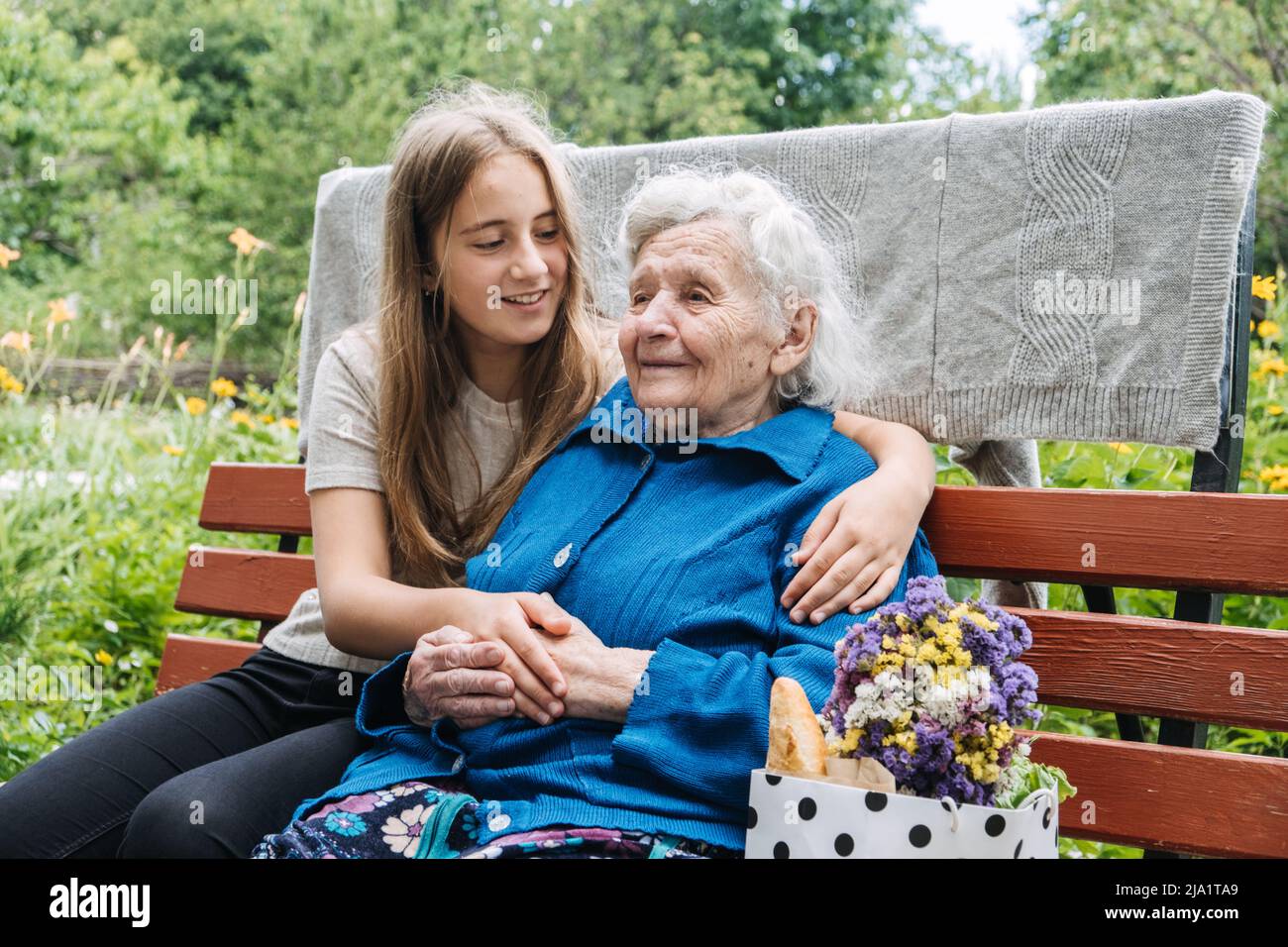 Grand-mère avec petite-fille sur fond de nature. Adolescente embrassant grand-mère à l'extérieur. Bonne fille petite-fille en visite embrassant Banque D'Images