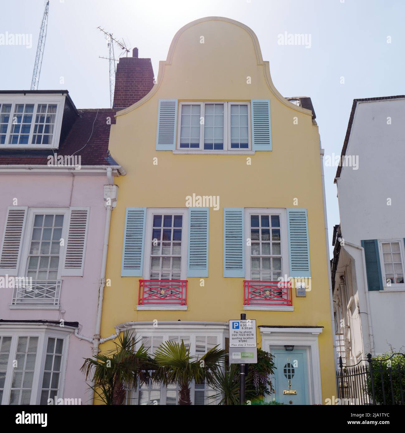 Jolie maison jaune avec un toit de forme inhabituelle et des volets de fenêtre bleu pastel au large de Kings Road à Chelsea. Banque D'Images
