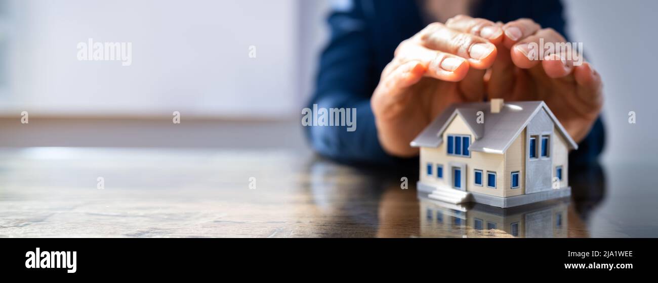Close-up of a person's hand protection Miniature House sur le bureau Banque D'Images